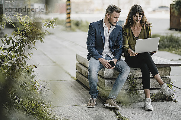 Geschäftsmann und gelegentliche Geschäftsfrau mit Laptop im Freien