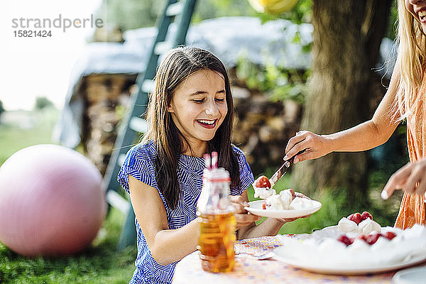 Mädchen erhält ein Stück Kuchen auf einer Geburtstagsfeier im Freien
