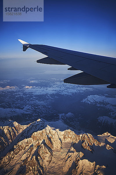 Frankreich,  Auvergne-Rhône-Alpes,  Tragfläche des Airbus A321 im Morgengrauen über den europäischen Alpen und dem Genfer See
