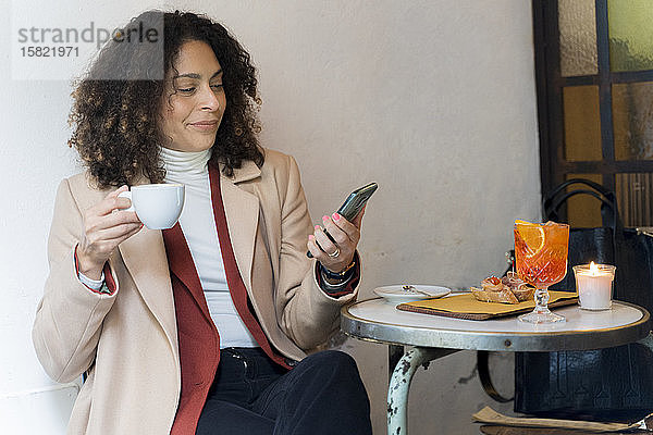 Frau betrachtet Handy in einem Café