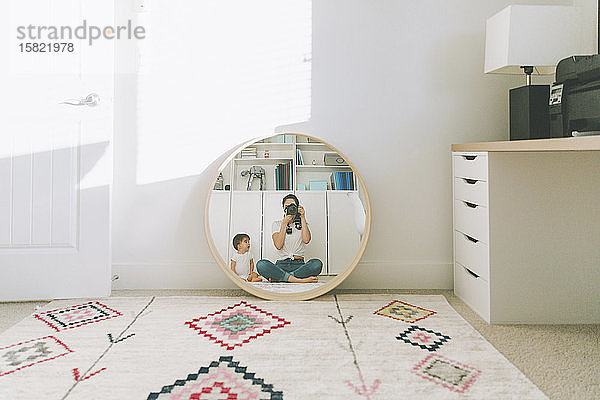 Spiegelung einer Mutter,  die sich und ihr Baby im Spiegel fotografiert
