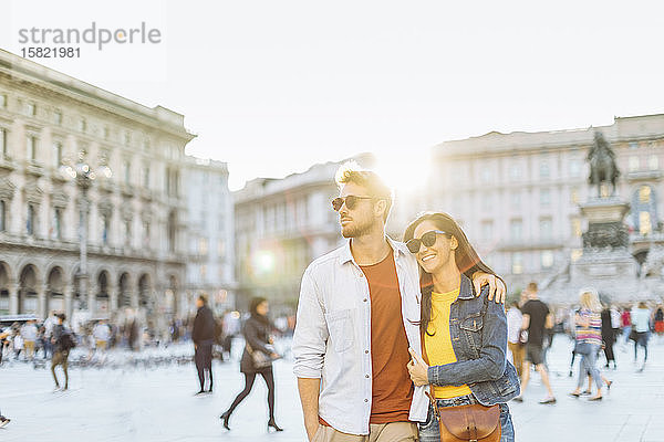 Glückliches junges Paar auf einem Platz in der Stadt bei Sonnenuntergang,  Mailand,  Italien
