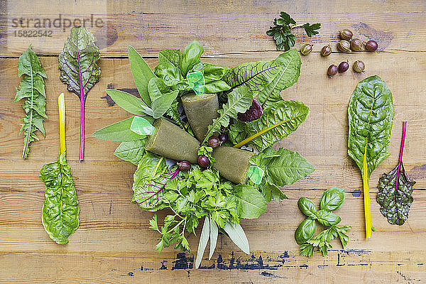 Draufsicht auf hausgemachtes grünes Gemüse und Kräuter-Eis am Holztisch