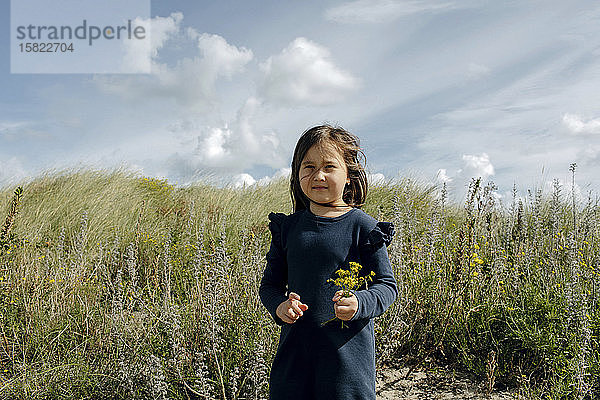 Porträt eines kleinen Mädchens mit gepflückten Blumen in den Dünen,  Den Haag,  Niederlande