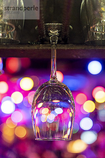 Leeres Weinglas hängt über der Theke mit Bokeh-Lichtern im Hintergrund