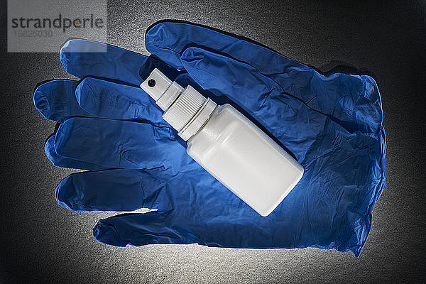 Nahaufnahme von blauen Operationshandschuhen und Flasche mit Desinfektionsspray