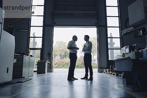 Zwei Männer unterhalten sich am offenen Tor in einer Fabrik