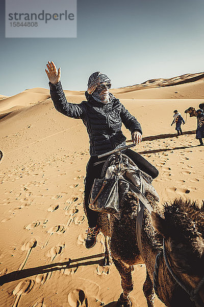 Menschen,  die auf Dromedaren durch die Wüste reiten