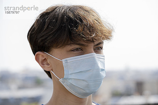 Nahaufnahme eines Teenagers mit blauer chirurgischer Maske im Freien