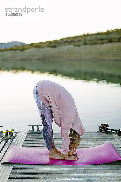 Junge Frau beim Yoga auf einem Steg