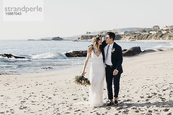 Glückliches Brautpaar beim Spaziergang am Strand