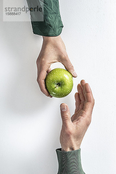 Draufsicht einer Frau,  die einem Mann einen grünen Apfel überreicht