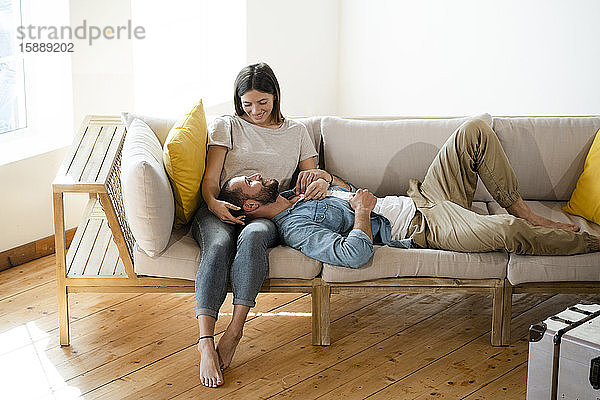 Zärtliches junges verliebtes Paar,  das sich zu Hause auf der Couch entspannt