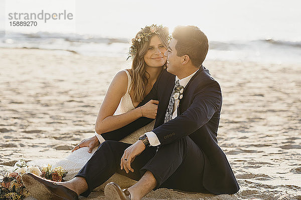 Glückliches Brautpaar sitzt am Strand