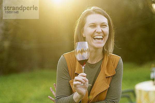 Glückliche Frau trinkt Rotwein auf dem Land