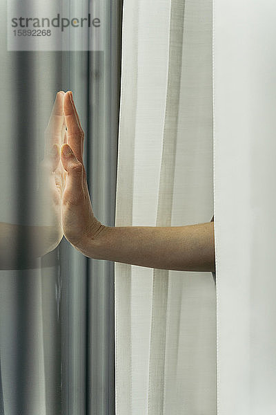 Hand einer Frau,  die eine Fensterscheibe berührt