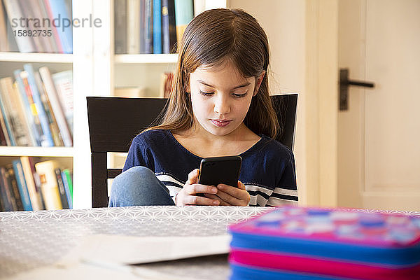 Mädchen macht Hausaufgaben mit Smartphone