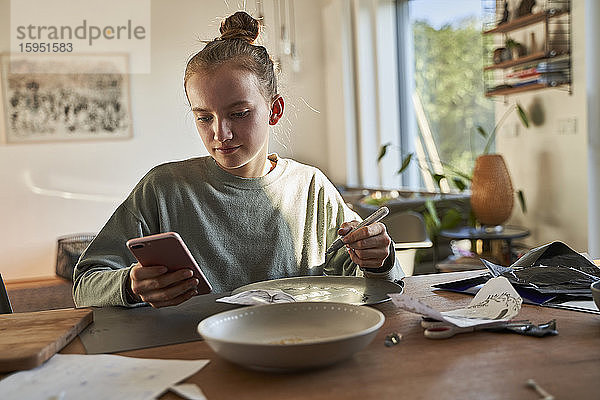 Mädchen zu Hause nutzt Smartphone für ein kreatives Online-Tutorial