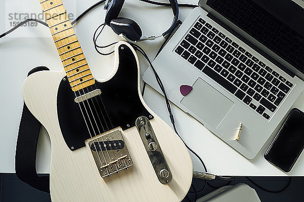 Draufsicht auf E-Gitarre,  Laptop,  Smartphone und Kopfhörer