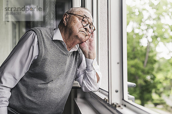 Porträt eines traurigen älteren Mannes,  der aus dem Fenster schaut