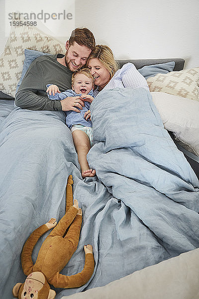 Familie kuschelt gemeinsam im Bett