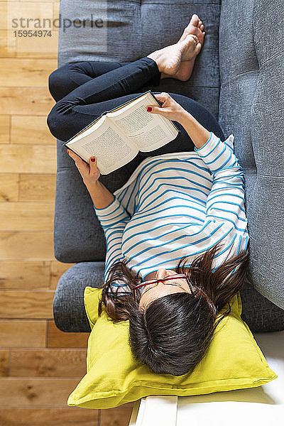 Frau entspannt sich auf dem Sofa und liest ein Buch
