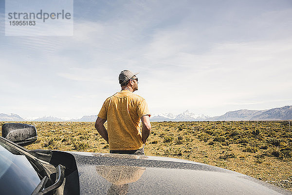 Rückansicht eines Mannes am Auto in einer abgelegenen Landschaft in Patagonien,  Argentinien