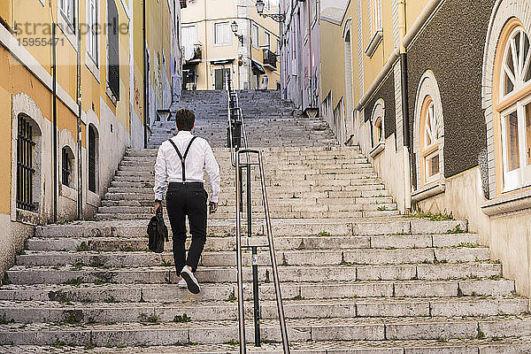 Rückansicht eines jungen Mannes beim Treppensteigen in der Altstadt,  Lissabon,  Portugal