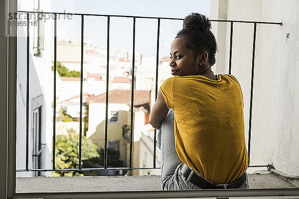 Junge Frau sitzt auf einem Balkon
