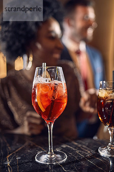 Cocktailglas auf der Theke in einer Bar mit glücklichen Menschen im Hintergrund