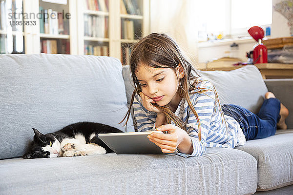 Porträt eines auf einer Couch liegenden Mädchens mit digitalem Tablett