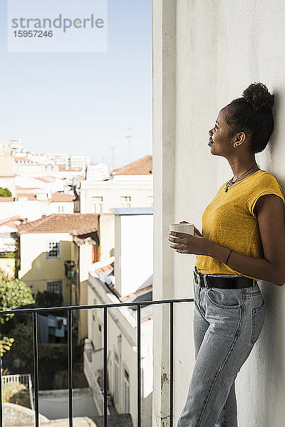 Junge Frau mit Kaffeetasse auf einem Balkon