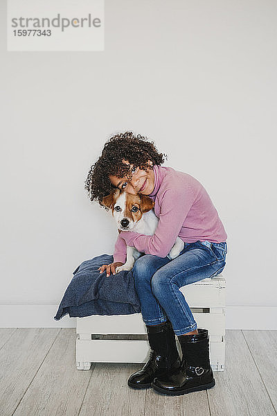 Porträt eines lächelnden kleinen Mädchens,  das seinen Hund knuddelt