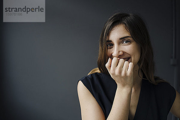 Porträt einer lachenden jungen Frau mit Hand vor dem Mund