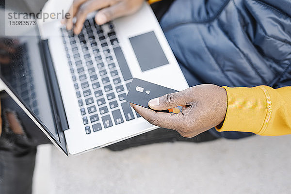 Nahaufnahme eines Mannes,  der einen Laptop und eine Kreditkarte zum Online-Shopping benutzt