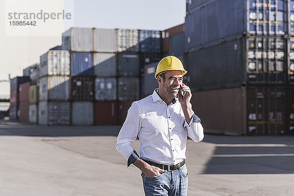 Porträt eines Geschäftsmannes am Telefon vor einem Frachtcontainer