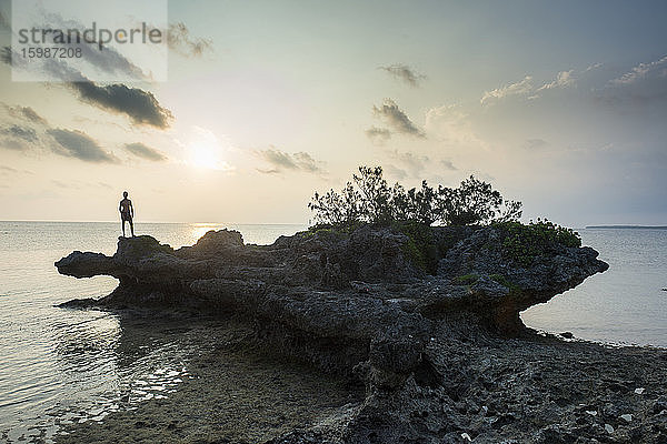 Mann auf einem Felsen an der Meeresküste in Ouvea,  Loyalitätsinseln,  Neukaledonien