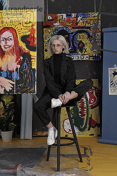 Porträt selbstbewusste junge Künstlerin im Atelier mit Gemälden