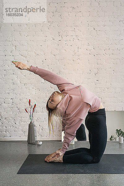Junge Frau übt im Yoga-Studio Kamelhaltung in Rückenbeuge