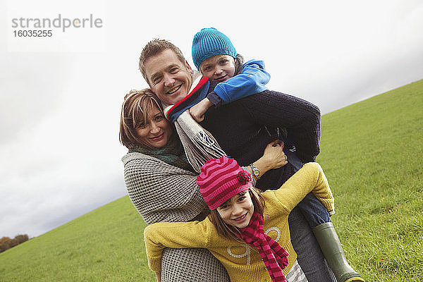 Porträt einer glücklichen Familie,  die sich im Grasfeld umarmt