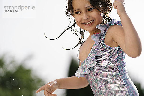 Porträt eines glücklichen kleinen Mädchens im Badeanzug im Freien