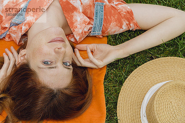 Schöne junge Frau entspannt sich auf Gras im Hinterhof