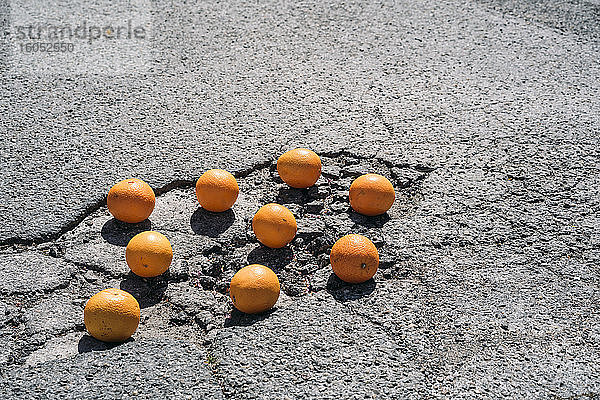 Gruppe von Orangen in Asphaltrissen liegend #