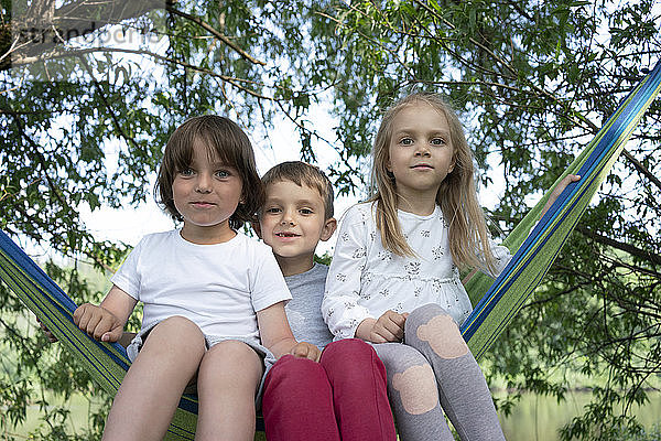 Niedliche Kinder sitzen auf Hängematte im Wald
