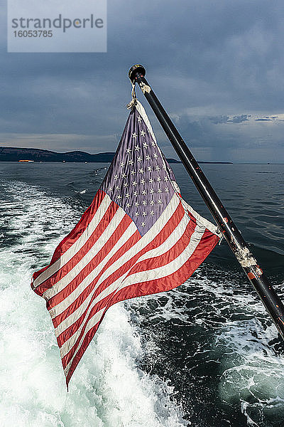 USA,  Washington,  amerikanische Flagge auf dem Rücken eines fahrenden Motorboots