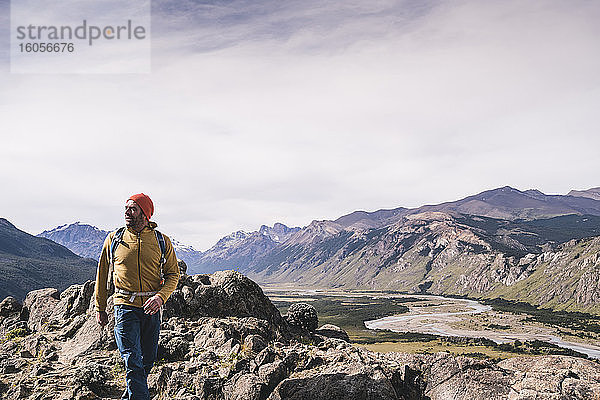 Männlicher Wanderer,  der in Patagonien,  Argentinien,  auf Felsen gegen Berge läuft