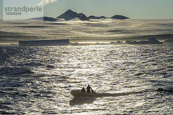 Touristen auf einem Schlauchboot bewundern die Küstenlinie der Tabarin-Halbinsel