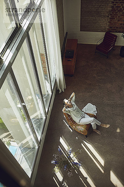 Älterer Mann entspannt sich auf einem Stuhl in einer Dachgeschosswohnung