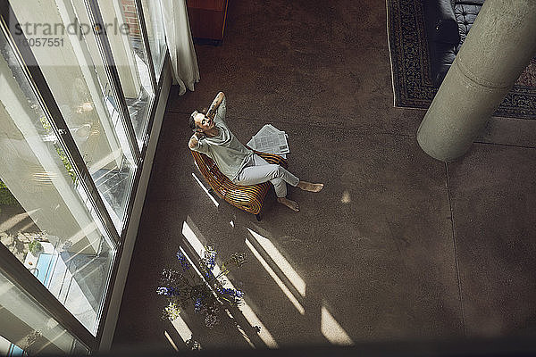 Älterer Mann entspannt sich auf einem Stuhl in einer Dachgeschosswohnung