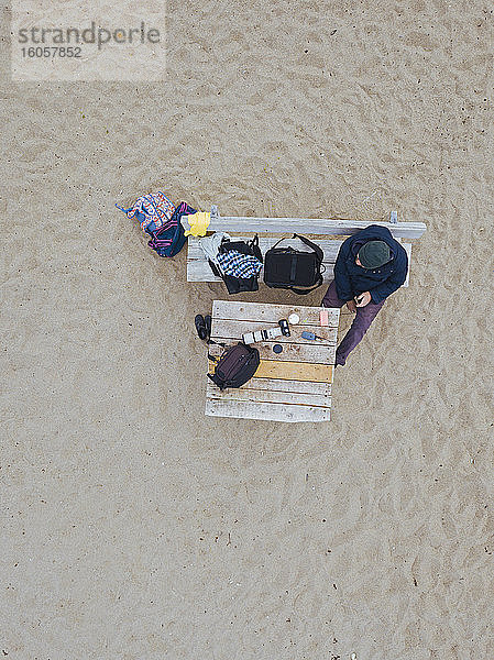 Luftaufnahme eines Mannes,  der sich auf einer Bank am Strand entspannt